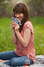 Young woman playing cards in orchard. Photo : Mike Kemp