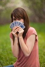 Young woman playing cards in orchard. Photo : Mike Kemp