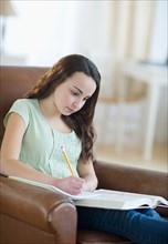 Portrait of teenage girl (14-15) doing homework.