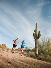 USA, Arizona, Phoenix, Mid adult man and young woman jogging on desert.