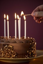 Studio shot of man igniting candles on chocolate birthday cake.