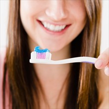Close-up of smiling young woman holding toothbrush. Photo : Jamie Grill Photography