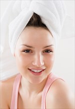 Studio portrait of smiling young woman with towel turban. Photo : Jamie Grill Photography