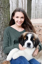 USA, New Jersey, Califon, Teenage girl (16-17) sitting with Saint Bernard puppy on laps, portrait.
