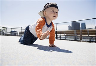 USA, New York City, Brooklyn, baby boy (0-1 years) crawling on sidewalk. Photo : Maisie Paterson