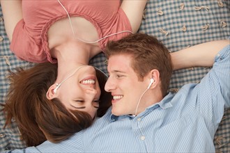 Young couple with mp3 player lying on blanket. Photo : Mike Kemp