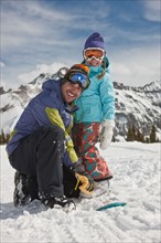 USA, Colorado, Telluride, Father and daughter (10-11) posing with snowboards in winter scenery.