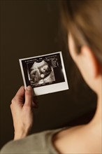 Woman holding ultrasonograph photo of baby. Photo : Rob Lewine