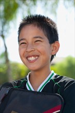 School boy (12-13) with bag, smiling. Photo : Noah Clayton