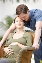 Pregnant woman sitting in wicker chair, with loving partner beside. Photo : Rob Lewine