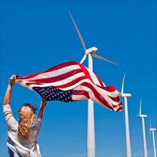 USA, California, Palm Springs, Woman weaving American flag with wind turbines in background. Photo
