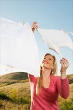 Woman hanging laundry on clothesline .