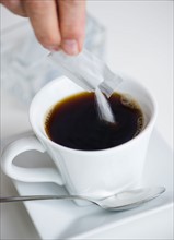 Man pouring sweetener into coffee.