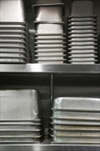 Close up food containers on shelves in commercial kitchen.