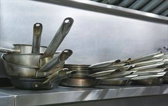 Close up frying pans on shelf in commercial kitchen.