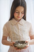 Girl (8-9) holding bird's nest.