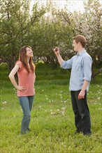USA, Utah, Provo, Young man photographing young woman in orchard. Photo : Mike Kemp