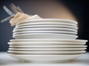 Stack of plates and forks, studio shot. Photo : Jamie Grill Photography