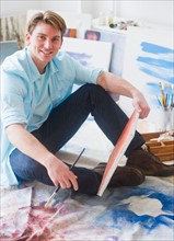 Portrait of young man painting picture in studio. Photo : Daniel Grill