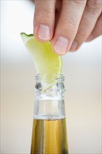 Man putting lemon slice into beer bottle.