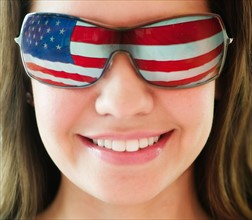 Woman wearing sunglasses reflecting US flag.