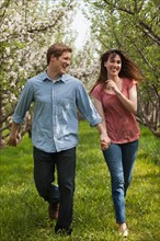 USA, Utah, Provo, Young couple walking through orchard. Photo : Mike Kemp