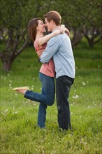 Young couple embracing in orchard. Photo : Mike Kemp