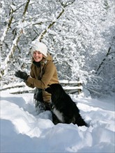 USA, Colorado, young woman playing with dog in snow. Photo : John Kelly