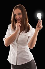 Young attractive businesswoman holding illuminated bulb. Photo : Mike Kemp