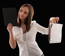 Young attractive businesswoman comparing financial results with financial column in newspaper.