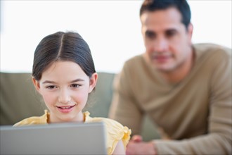 Daughter (8-9) and father using laptop .