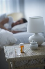 Sleeping pills bedside table with woman sleeping in background.