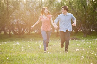USA, Utah, Provo, Young couple running through orchard. Photo : Mike Kemp