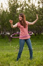 USA, Utah, Provo, Young woman using plastic hoop in orchard. Photo : Mike Kemp