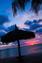 Aruba, silhouette of palapa on beach at sunset. Photo : Daniel Grill