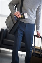 Businessman holding passport and suitcase.
