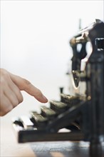 Close-up of man's hand typing on antique typewriter.