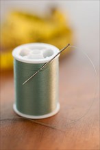 Close-up of green thread spool with needle.