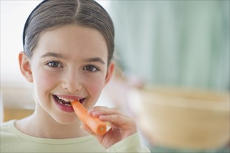 Girl (8-9) eating carrot.