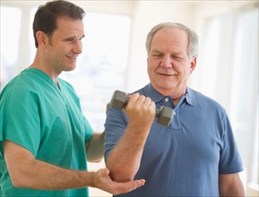 Man assisting senior man weight lifting.