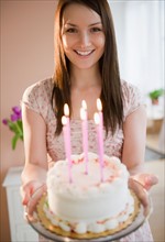 Young woman holding birthday cake. Photo : Jamie Grill Photography