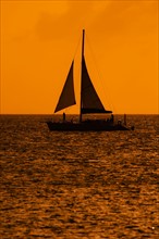 Silhouette of sailboat at sunset. Photo : Daniel Grill