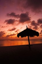 Aruba, silhouette of palapa on beach at sunset. Photo : Daniel Grill