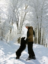 USA, Colorado, young woman playing with dog on snowy road. Photo : John Kelly