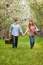 USA, Utah, Provo, Young couple with picnic basket in orchard. Photo : Mike Kemp