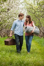 USA, Utah, Provo, Young couple with picnic basket in orchard. Photo : Mike Kemp