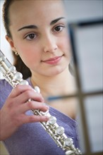 Teenage girl (14-15) holding flute .