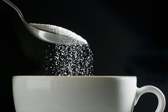 Studio shot of sugar poured into coffee cup.