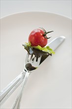 Cherry tomato and lettuce leaves on fork.