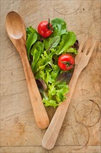 Salad leaves and wooden spoon and fork.